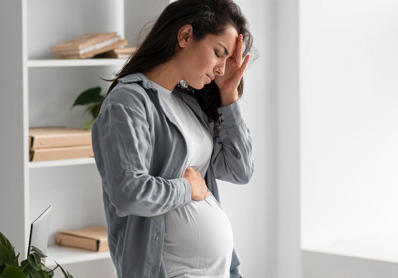 grávida segura a sua barriga com dor intestinal
