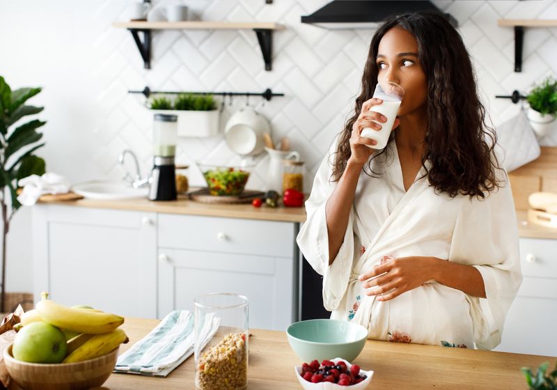 Mulher bebendo leite em sua cozinha